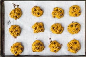 Baked pumpkin chocolate chip cookies on a parchment paper lined baking sheet
