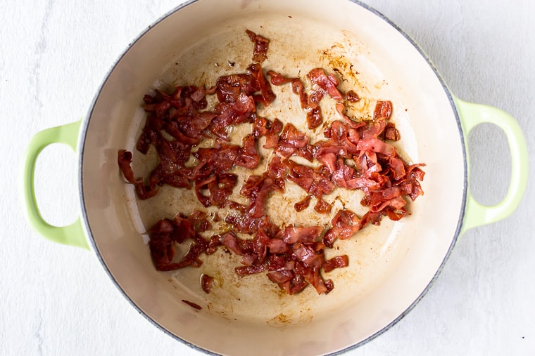 Turkey Bacon cooking in a Dutch oven over a white background
