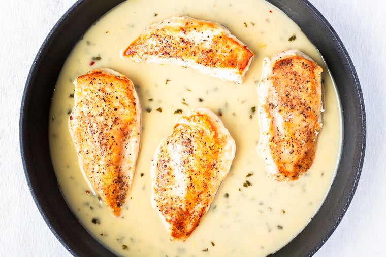 4 Pan seared chicken breasts and coconut lime sauce in a black skillet