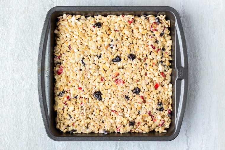 Rice Krispie treats in a square baking pan over a white background