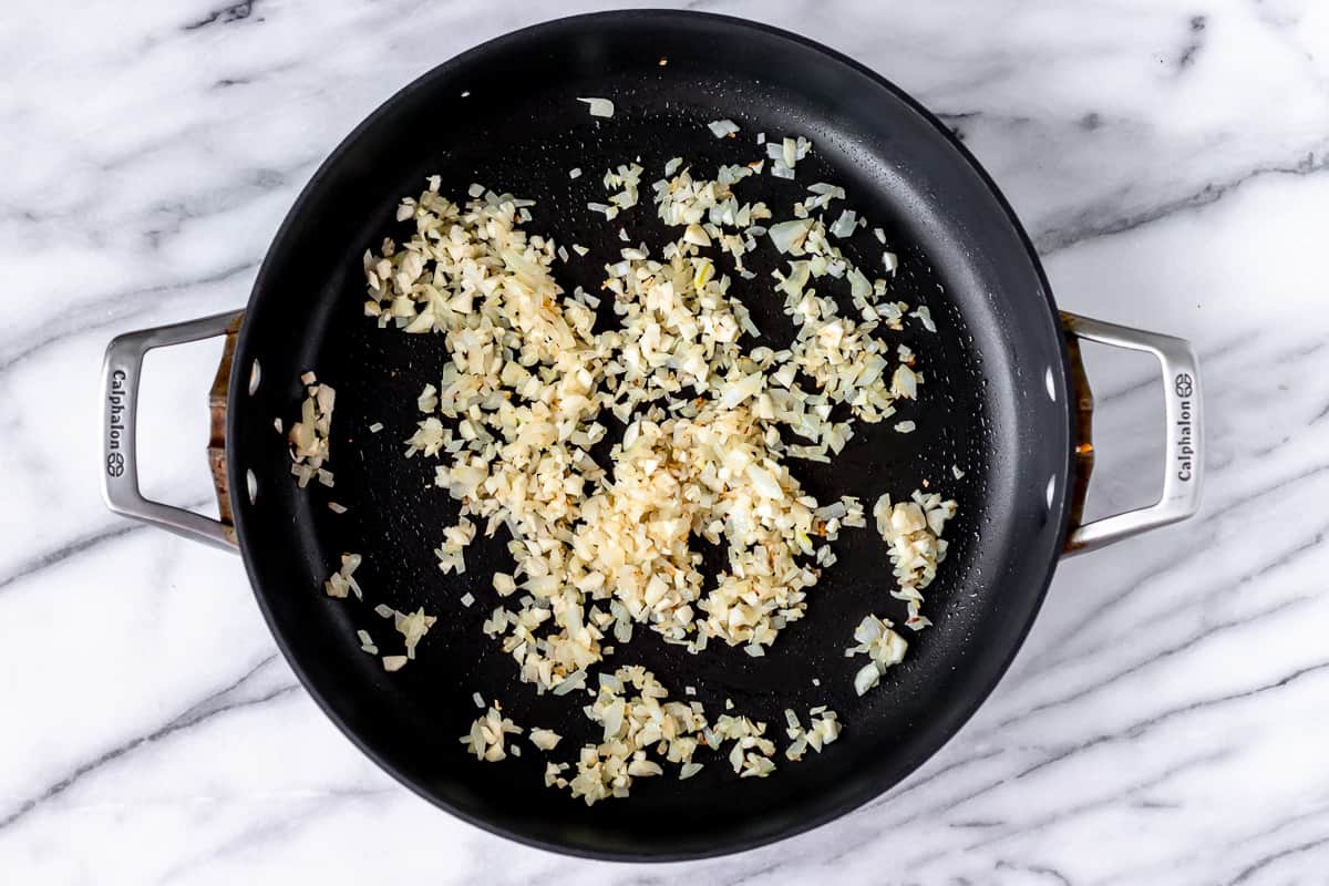 Onion and garlic cooking in a black skillet.