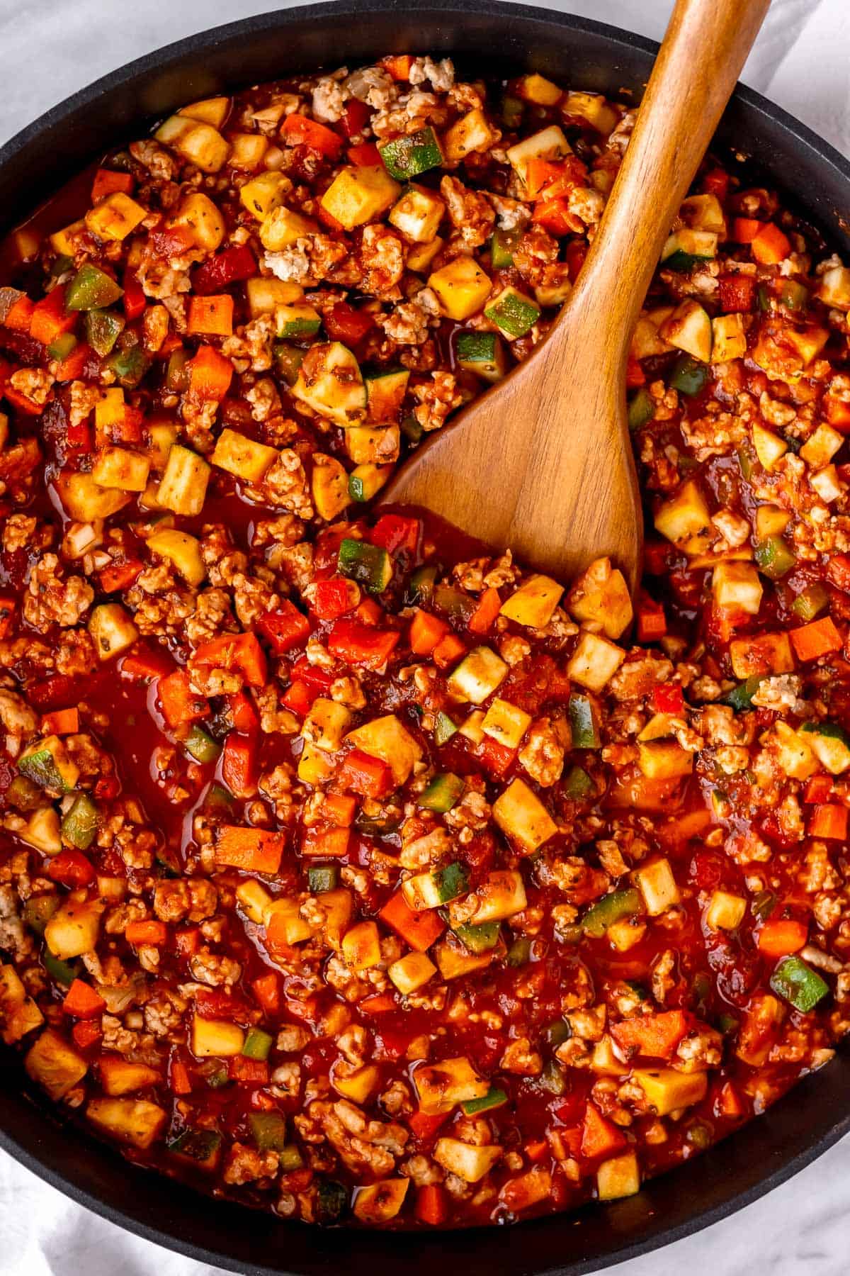 Vegetable spaghetti sauce in a skillet with a wood spoon in it.