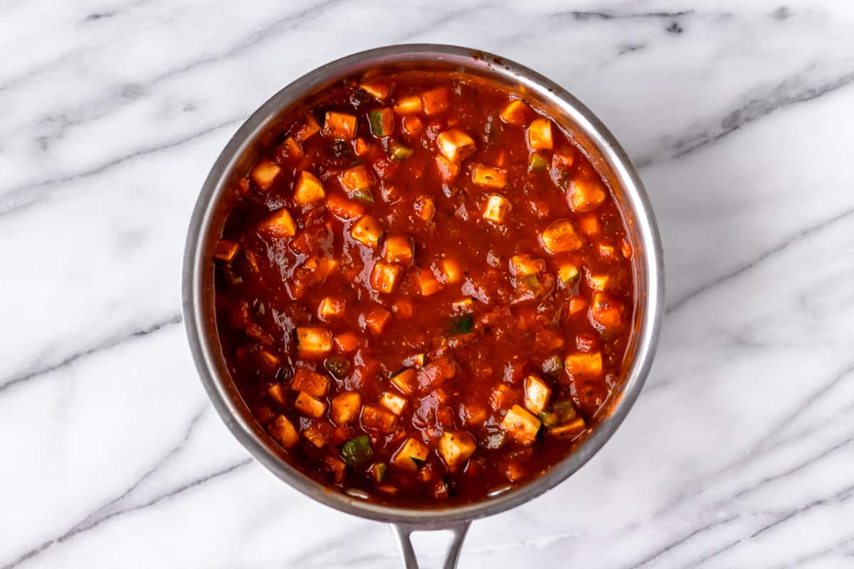 Spaghetti sauce with diced vegetables in it in a saucepan. 