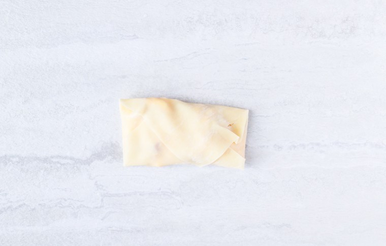 A fully wrapped egg roll on a white background