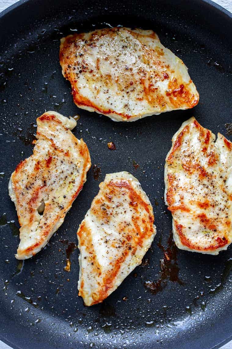 4 Chicken breasts cooking in a black skillet