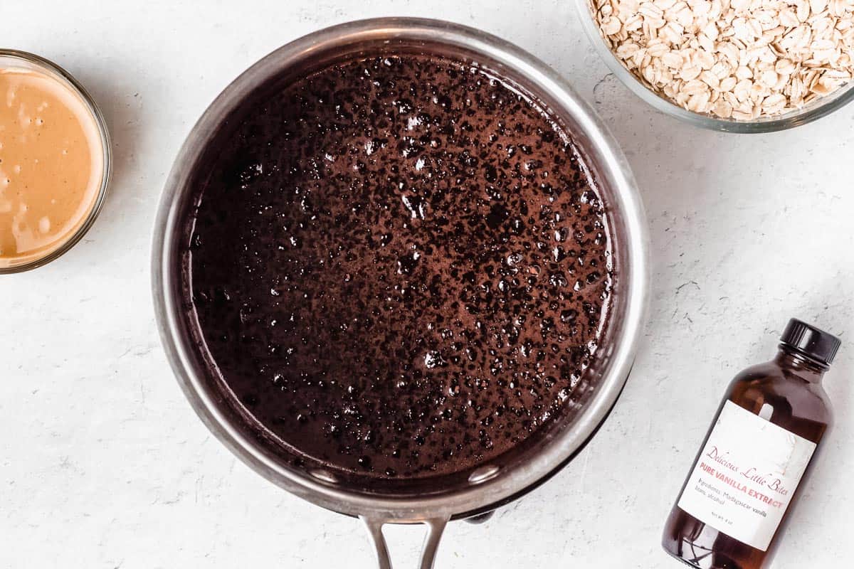 Chocolate mixture in a saucepan with other ingredients around it on a white background