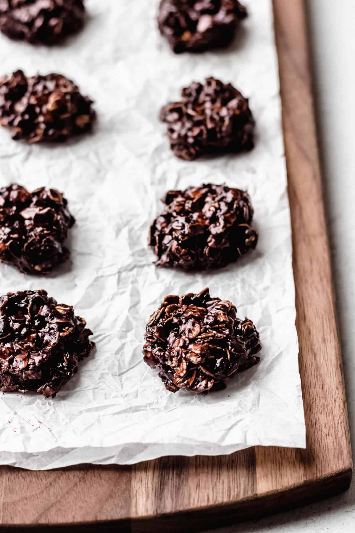 Dark Chocolate No-Bake Cookies on parchment paper on a wood board