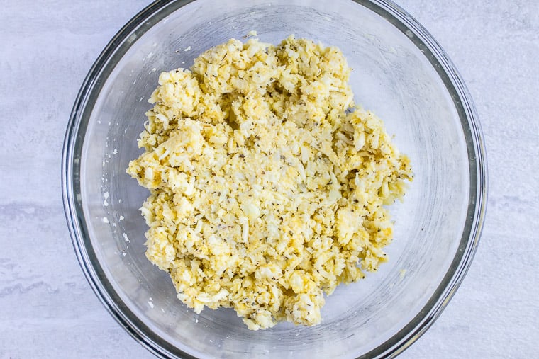 Cauliflower dough in a glass bowl over a white background