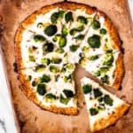 Overhead of a ricotta pizza on a pizza stone with one slice pulled away some.