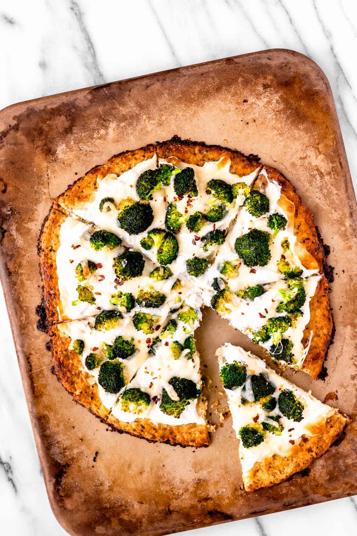 Overhead of a ricotta pizza on a pizza stone with one slice pulled away some.