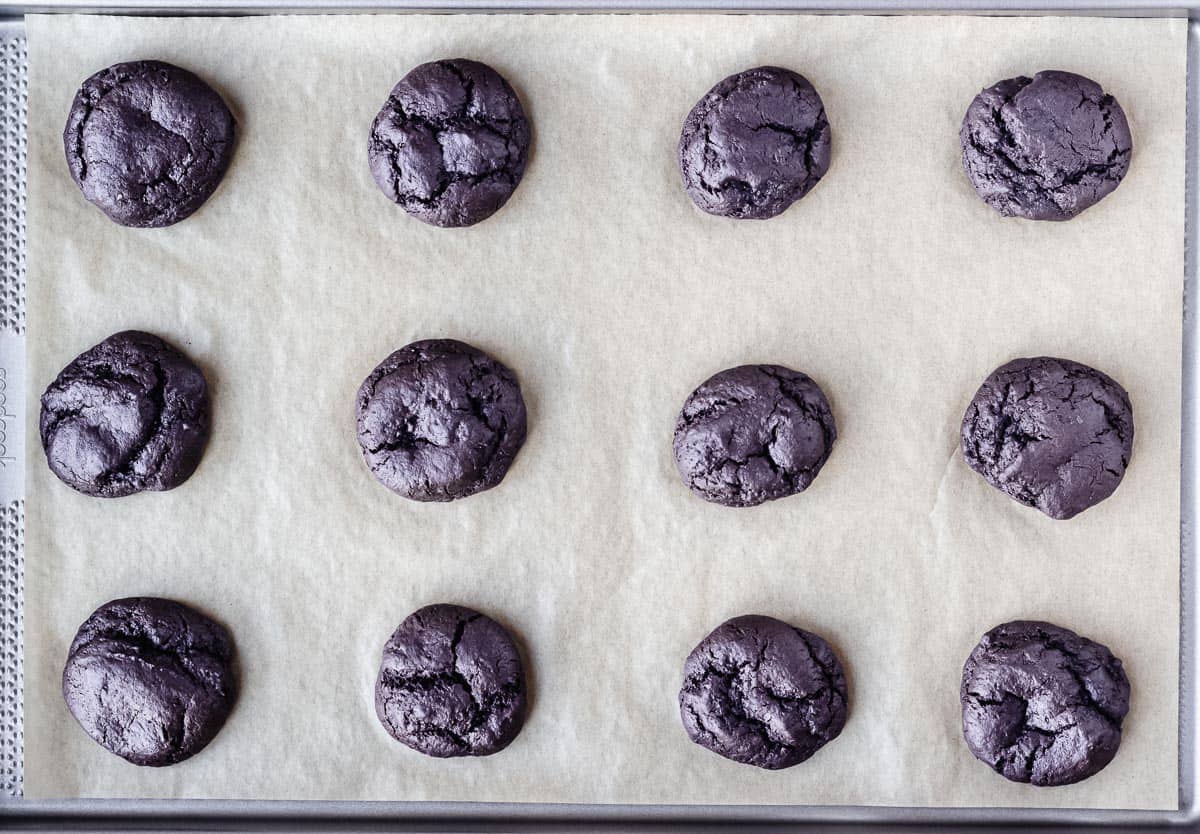 Baked dark chocolate cookies on a baking sheet lined with parchment paper