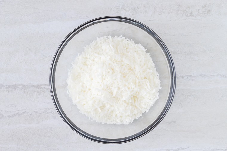 A bowl of shredded coconut over a white background