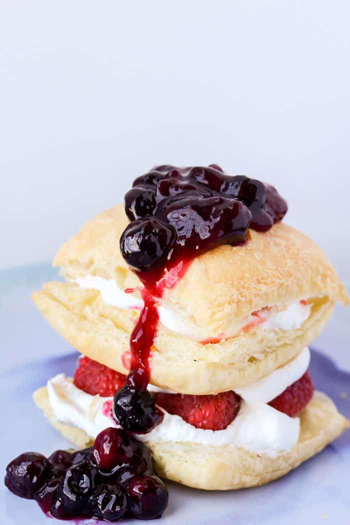 A Mixed Berry Puff Pastry Napoleon on a blue plate with a gray background
