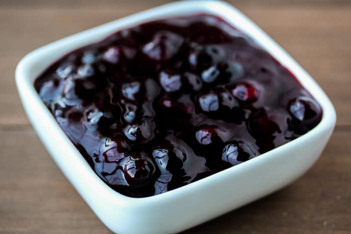 Blueberry Sauce in a White square Bowl over a wood background