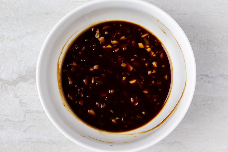 A white bowl with Asian sauce in it over a white background