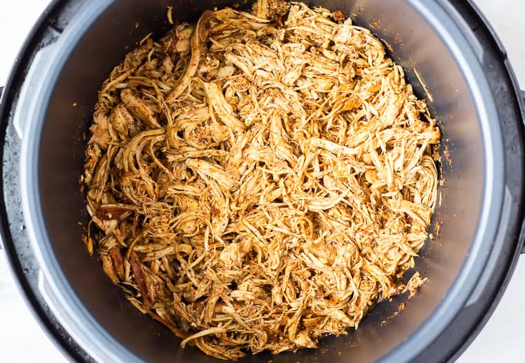 Overhead shredded chicken for tacos in a round slow cooker instant pot