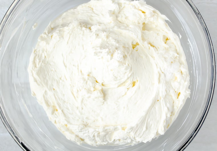 Cream cheese and whipped topping mixture in a glass bowl over a white background
