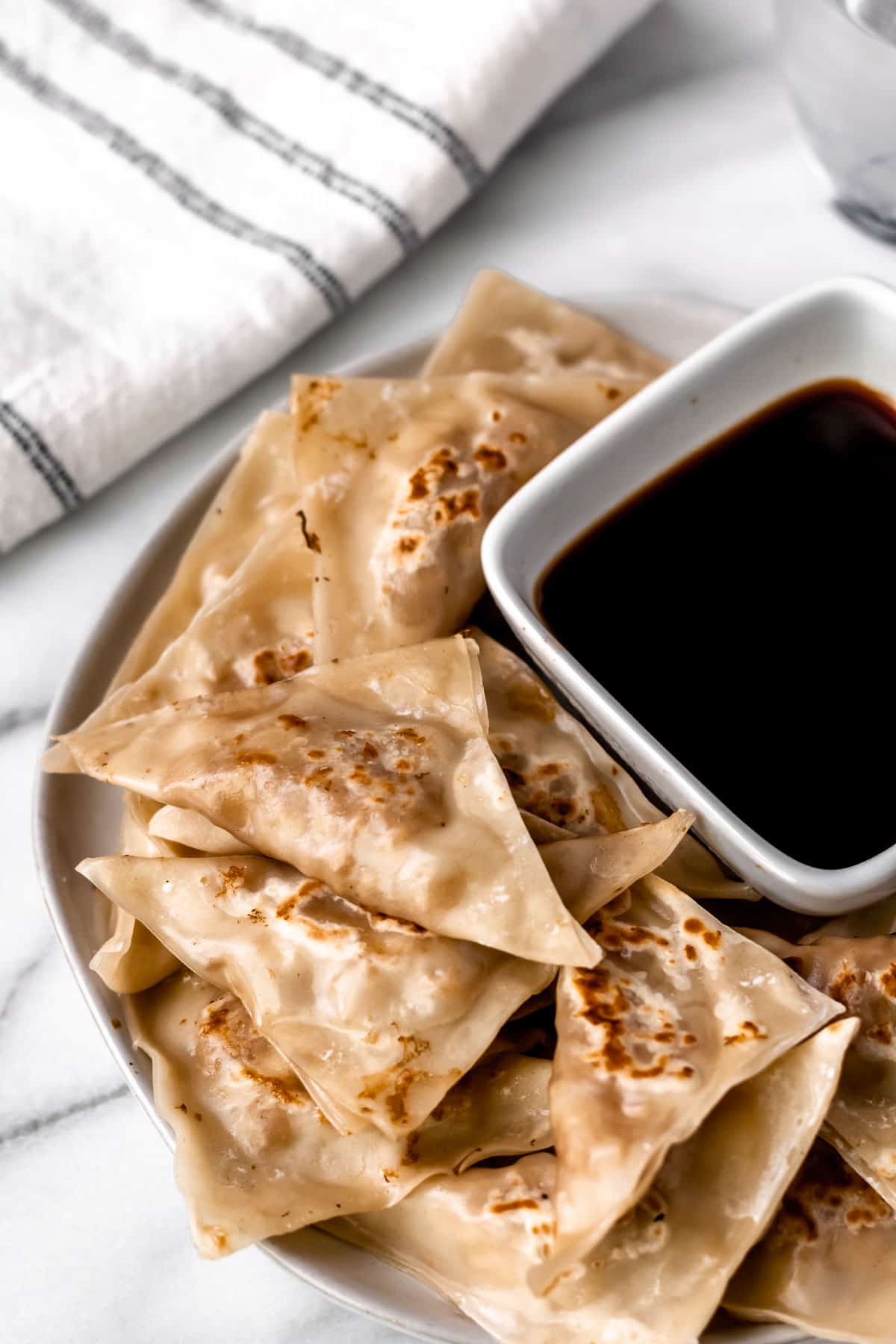 Potstickers on a plate with a bowl of dipping sauce.