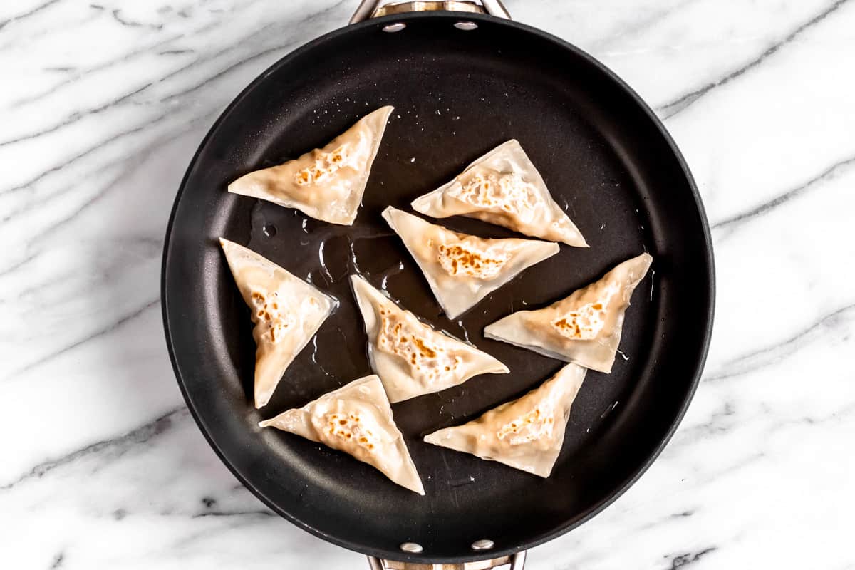 Cooked potstickers in a skillet.