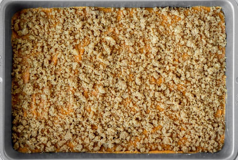 Pumpkin coffee cake in a pan with a crumb topping on it before baking