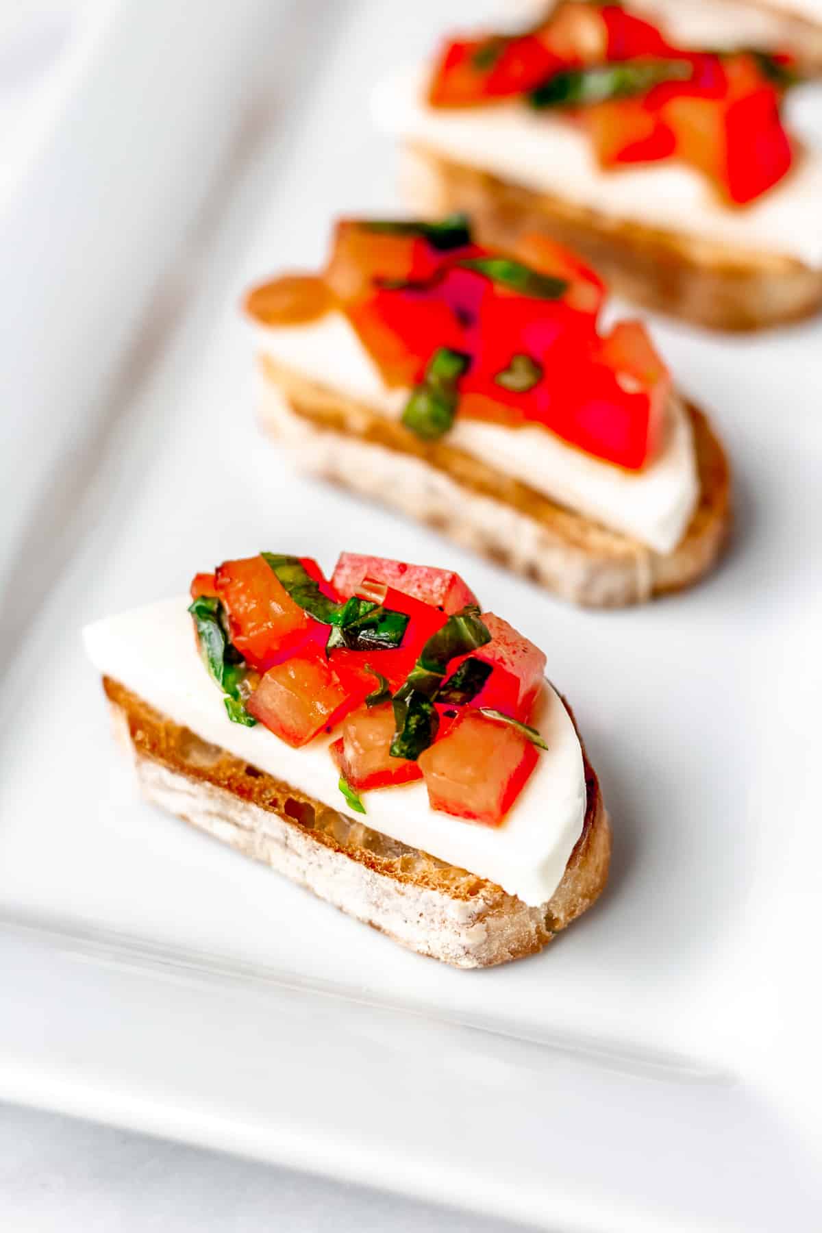 Bruschetta on toast on a white serving dish.