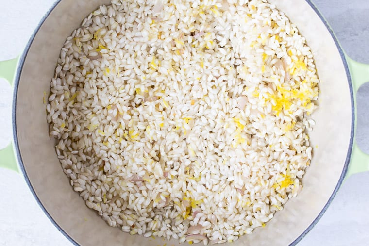 Rice and lemon zest in a Dutch Oven over a white background