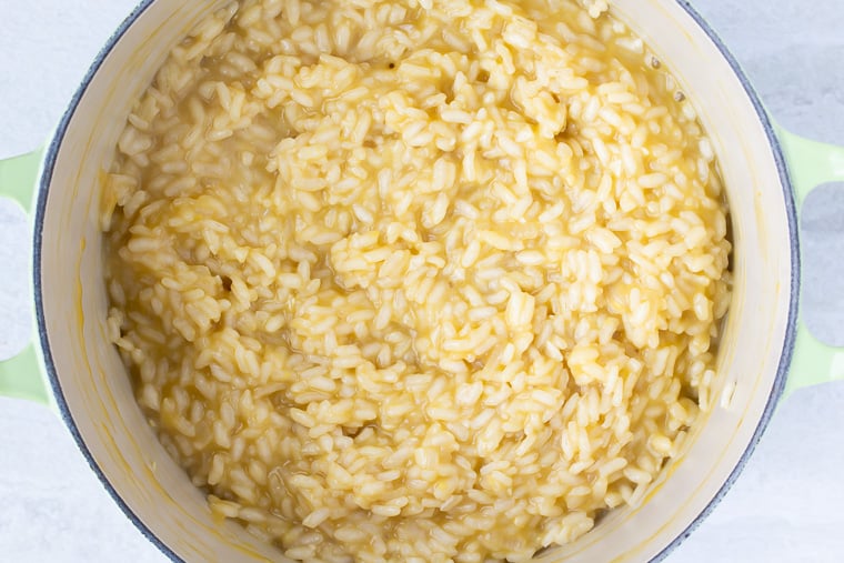 Risotto cooked with stock in a Dutch Oven over a white background
