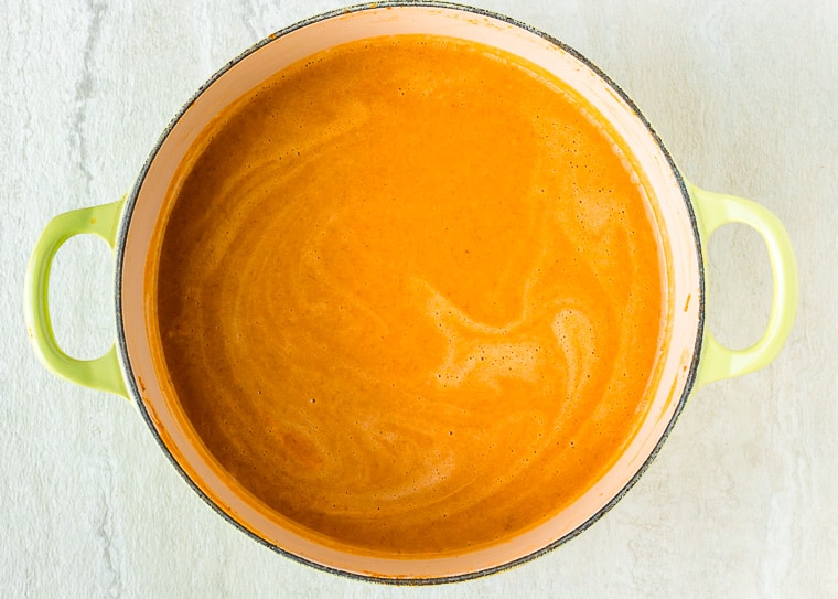 Creamy butternut squash soup in a Dutch oven over a white background