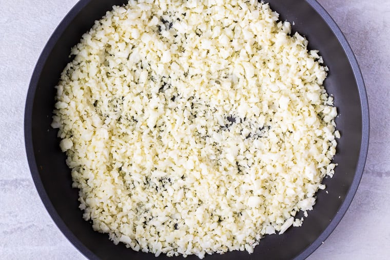 Cooked cauliflower rice in a black skillet