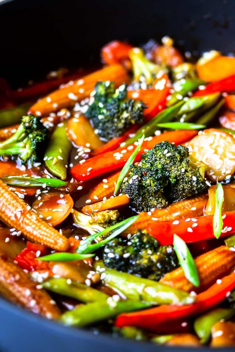 Close up of stir fry vegetables in sauce in a deep, black skillet