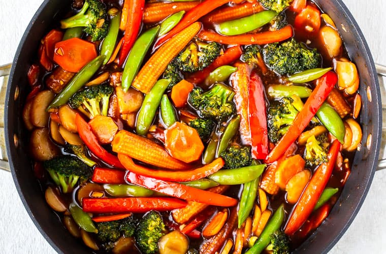 Stir fry sauce and vegetables in a deep, black skillet