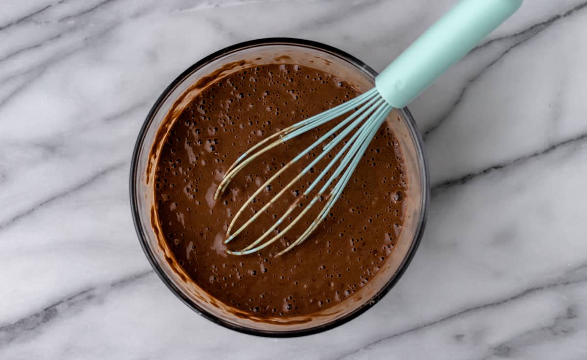 Chocolate waffle batter in a glass bowl with a whisk.