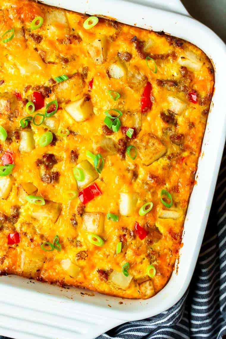 Overhead of a Breakfast Sausage Casserole in a white casserole dish with a blue and white striped towel around the bottom and side