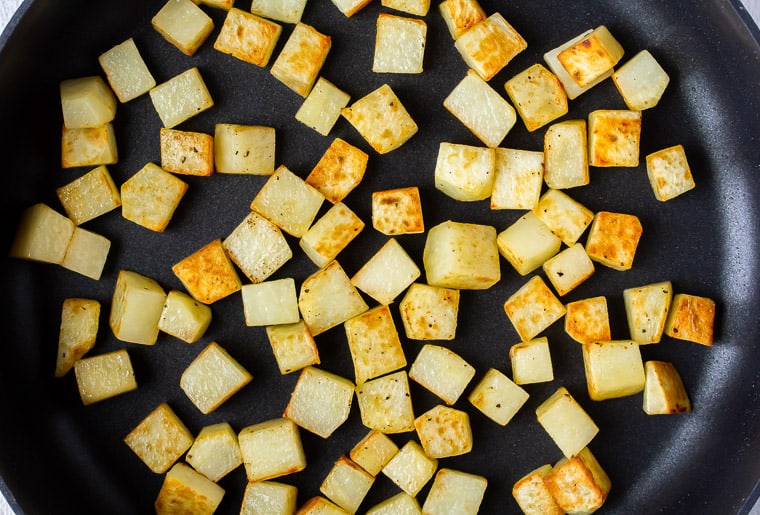 Cooked cubed potatoes in a black skillet