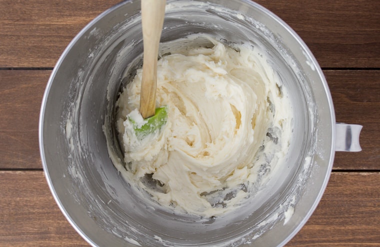 Vanilla Buttercream in a silver bowl with a green and wood spatula
