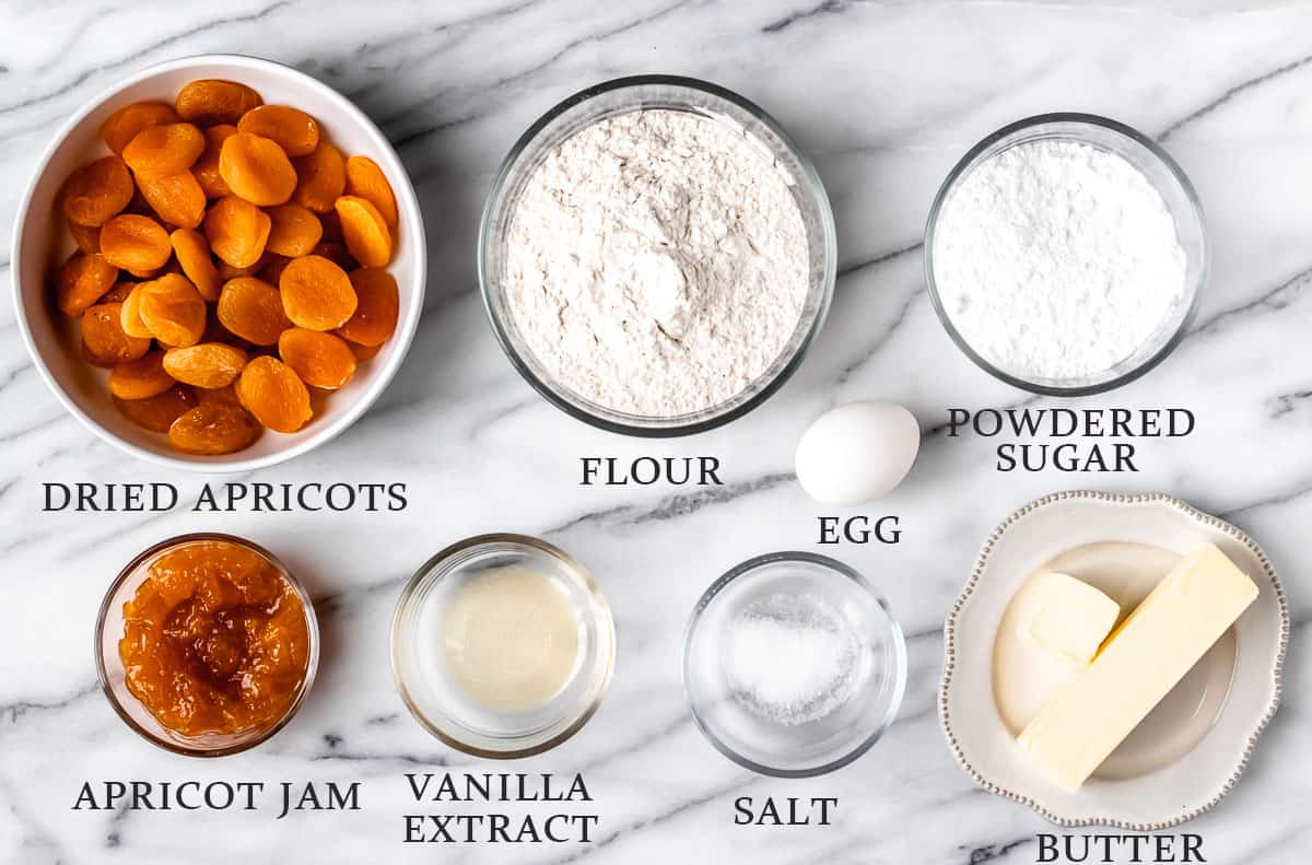 Ingredients needed to make an apricot tart on a marble background with text overlay.