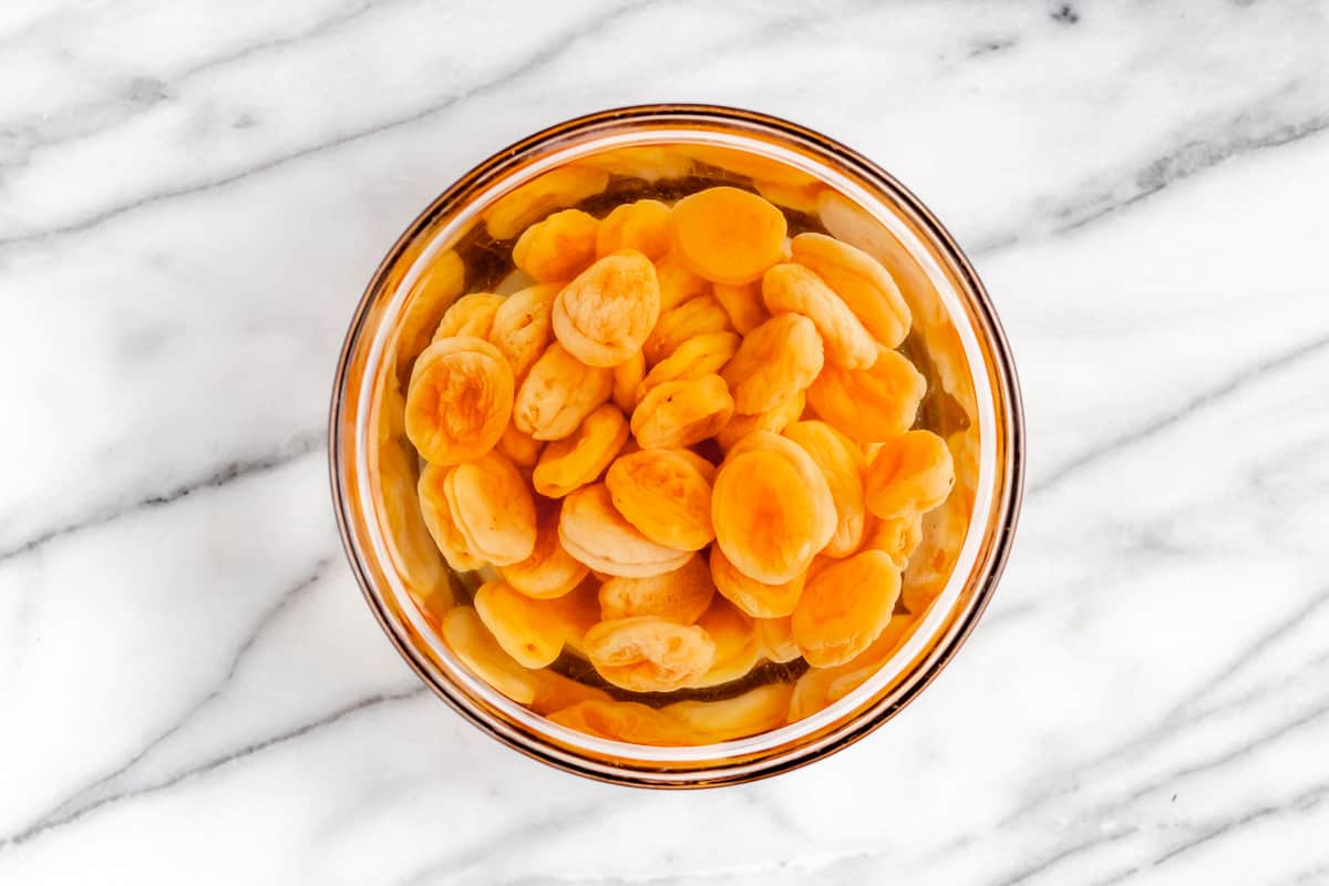 Dried apricots in a glass bowl of hot water.
