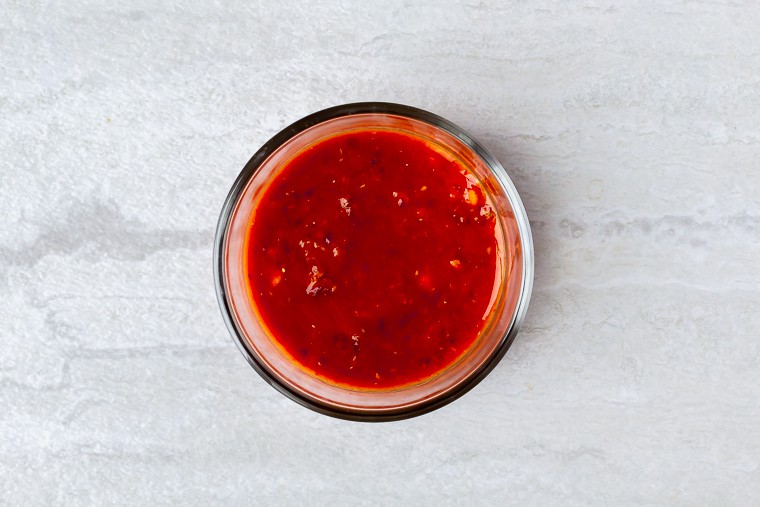 Orange chipotle sauce in a small glass bowl on a white background
