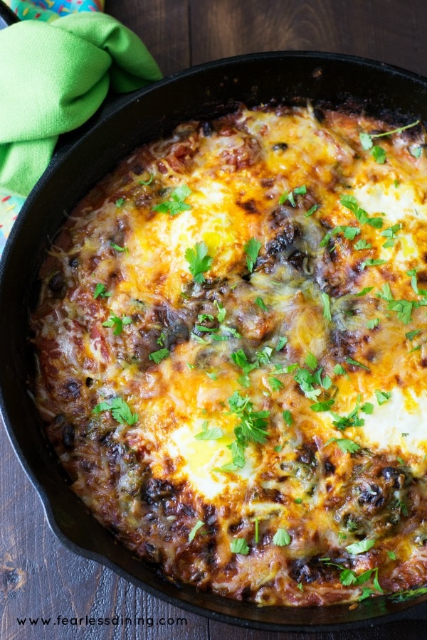 Mexican Shakshuka in a Black Skillet with a Green Towel on a Wood Background