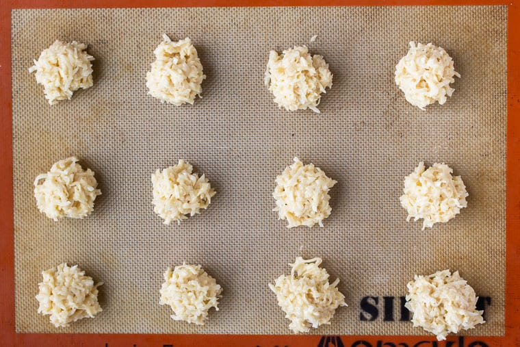 Coconut Macaroons rolled into balls on a baking sheet with a silpat bake before baking