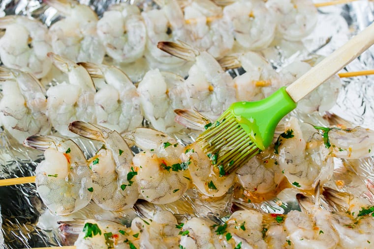 Basting shrimp skewers with sweet chili lime sauce