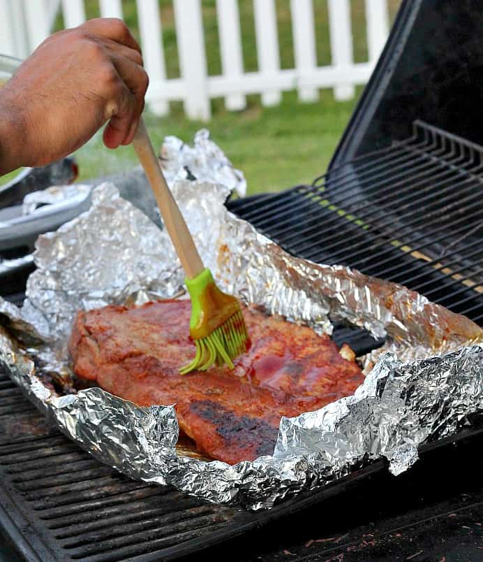 Basting a rack of Ribs on a grill with the Honey Barbecue Sauce 