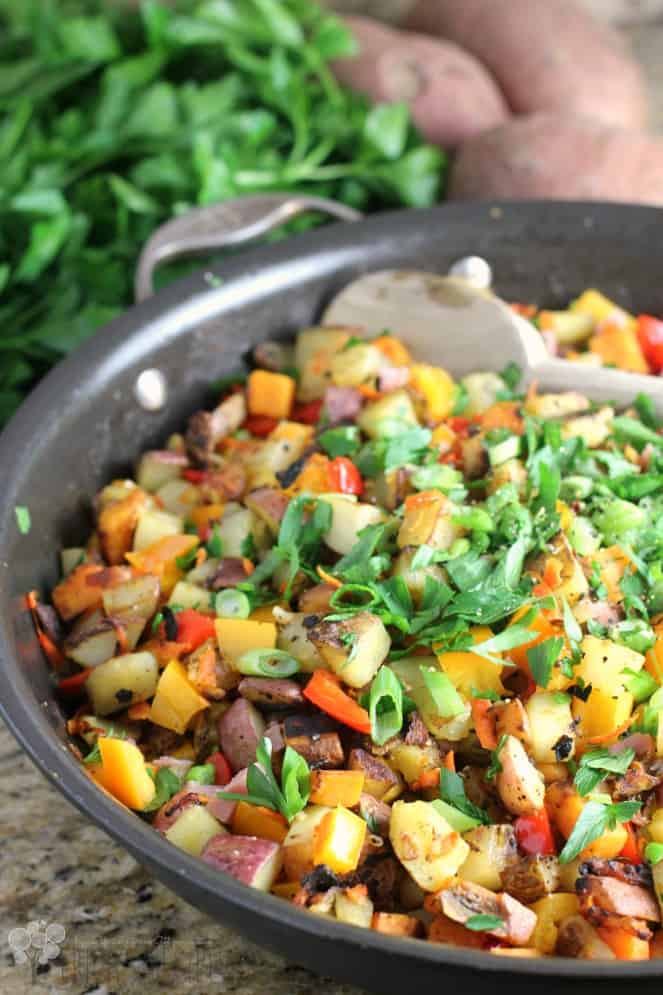 Three Potato Hash in a Black Skillet with Fresh Herbs and Potatoes in the Background