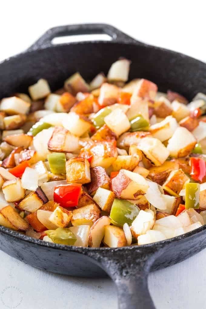 Close up of potatoes and peppers in a black skillet