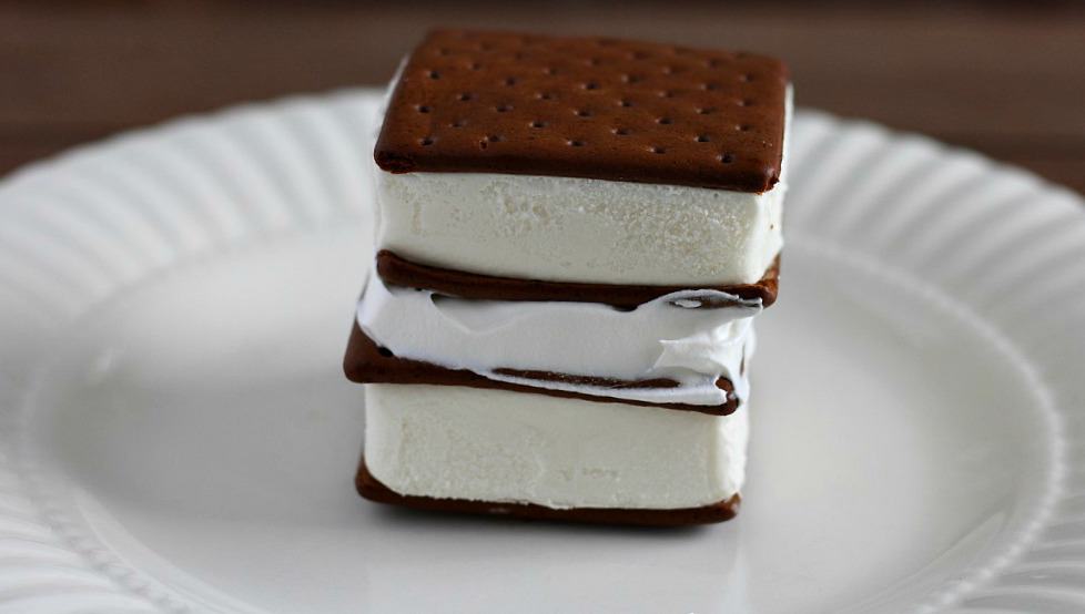 2 ice cream sandwiches stacked on top of each other with whipped topping between them on a white plate