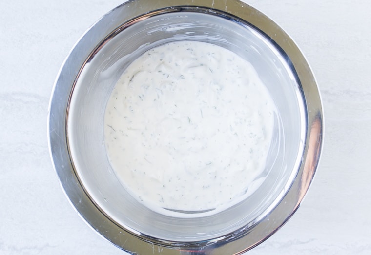 Lemon Tarragon Dressing for potato salad in a silver bowl over a white background