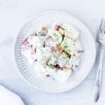 A white plate with Lemon Tarragon Potato Salad with a fork and white napkin on a white background