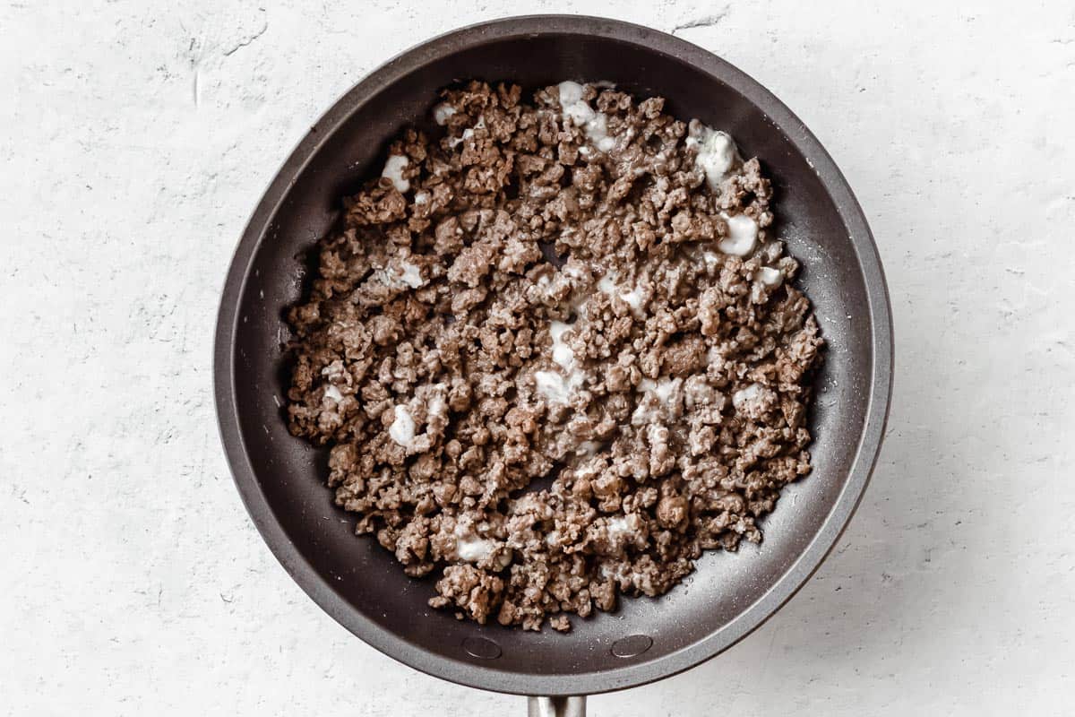 Ground beef and blue cheese in a small skillet over a white background