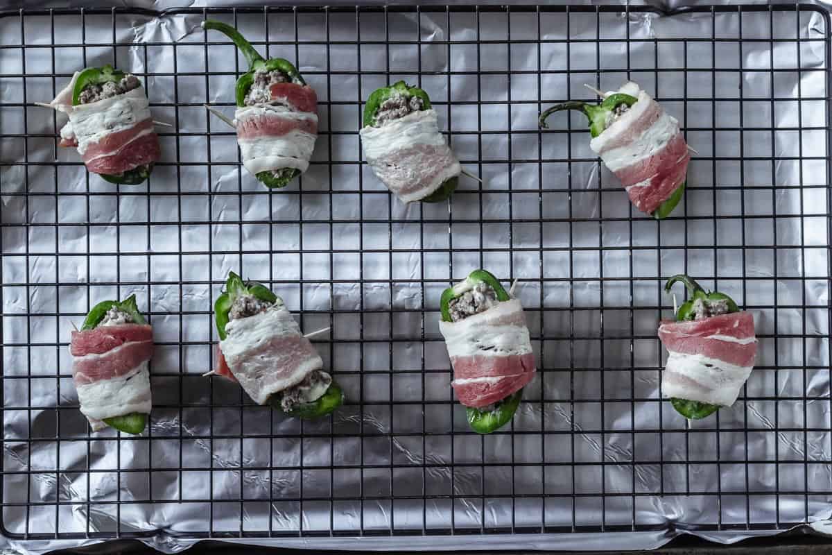 Jalapeno poppers on a wire rack over an aluminum foil lined baking sheet