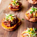 A wood board with 6 bbq pulled pork sweet potato rounds on it